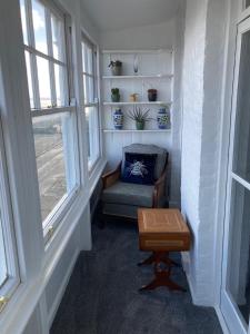 um quarto com uma cadeira, uma mesa e janelas em Paragon Home em Ramsgate