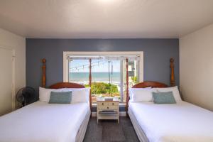 two beds in a room with a view of the ocean at Tides Oceanview Inn and Cottages in Pismo Beach
