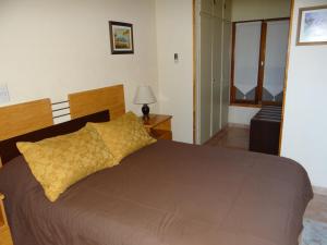 ein Schlafzimmer mit einem großen Bett und einem gelben Kissen in der Unterkunft Temporario Neny in Puerto Madryn