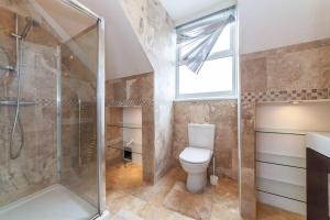 a bathroom with a toilet and a shower and a window at 2 Bedroom Duplex Apartment in London