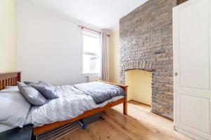 2 Bedroom Duplex Apartment في لندن: سرير في غرفة بجدار من الطوب