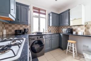 a kitchen with blue cabinets and a washing machine at 2 Bedroom Duplex Apartment in London
