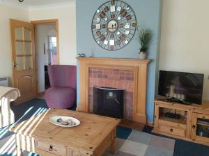 a living room with a fireplace and a clock on the wall at Rowan Cottage Highland retreat near Fort William in Spean Bridge