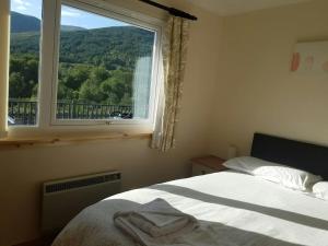 a bedroom with a bed and a window with a view at Rowan Cottage Highland retreat near Fort William in Spean Bridge