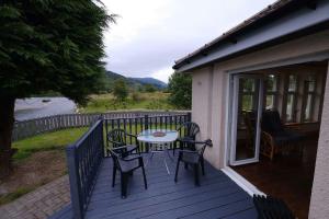 a patio with a table and chairs on a deck at Rowan Cottage Highland retreat near Fort William in Spean Bridge