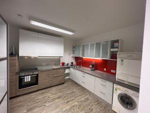 a large kitchen with white cabinets and red accents at Appartment in Kammerl in Schörfling