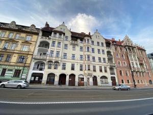 a large building with cars parked in front of it at Central Rooms Apartment in Toruń