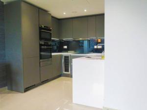 a kitchen with gray cabinets and a white counter at Club White London Bridge One Bedroom Apartment in London