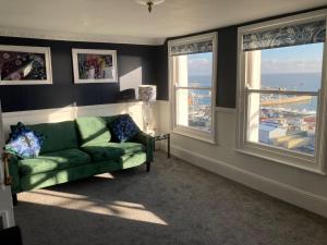 a living room with a green couch and two windows at Paragon Home in Ramsgate