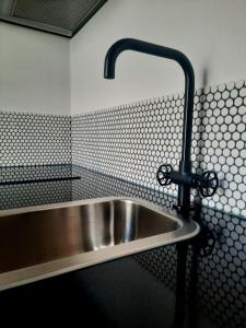 ein Waschbecken aus Edelstahl in einem schwarz-weißen Bad in der Unterkunft Casa A Júlia In Faro's Heart in Faro