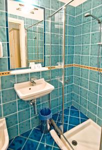 a blue tiled bathroom with a sink and a mirror at Hotel Capital in Cupra Marittima