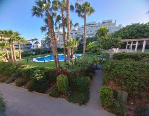 a garden with a swimming pool and palm trees and bushes at Altos del Toril 2 habitaciones Wifi y Parking in Torremolinos