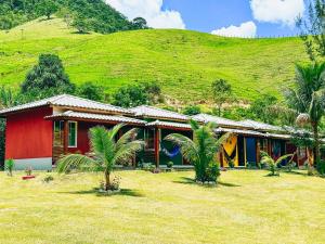 萨纳Pousada Sítio da Floresta的山前有棕榈树的红色房子