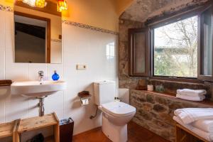 een badkamer met een toilet, een wastafel en een raam bij Mas Rubió in Joanetes