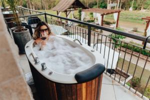 une femme assise dans une baignoire avec un verre de vin dans l'établissement LOTE20 Hotel Boutique, à Bento Gonçalves