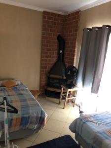 a living room with a brick fireplace and a bed and a bed sidx sidx sidx at Hospedagem Maria Joana in Atibaia