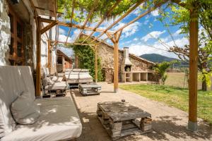 an outdoor patio with a wooden pergola and a table at Mas Rubió in Joanetes