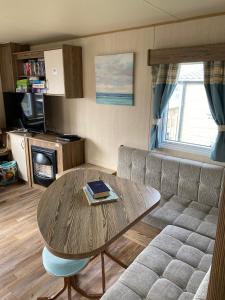 Setons Getaway في Port Seton: غرفة معيشة مع طاولة وأريكة