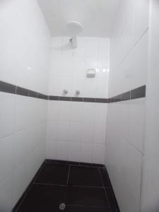una ducha de azulejos blancos con una luz en el techo en America Guest House, en Cusco