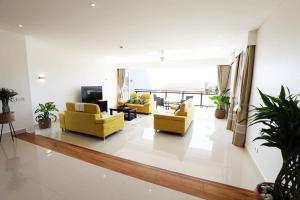 a living room with two yellow chairs and a television at Private Large VIP bedroom with en-suite in shared Deluxe Pool villa by Cliffhanger in Mahe