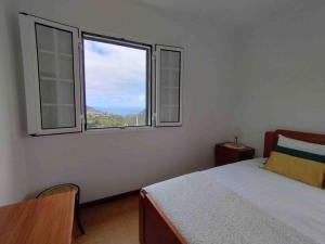 een slaapkamer met een bed en een groot raam bij Terra Batista house in Porto da Cruz