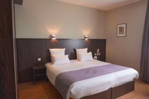 a bedroom with a large bed with white sheets and pillows at Best Western Plus Le Canard sur le Toit in Colomiers