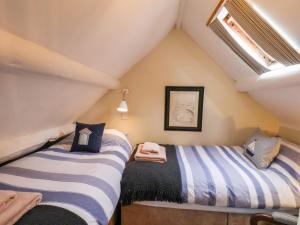 two beds in a attic room with a window at Delft Cottage in Robin Hood's Bay