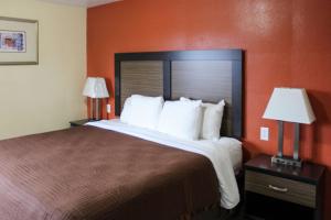 a hotel room with a large bed and two lamps at Rodeway Inn Medford South I-5 in Medford