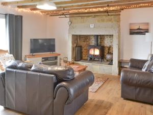 a living room with a leather couch and a fireplace at Beas Cottage in Cresswell