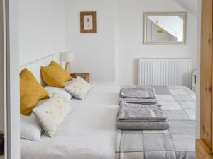 a white bedroom with a bed with yellow pillows at Beas Cottage in Cresswell