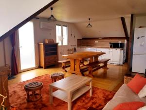 ein Wohnzimmer mit einem Holztisch und einer Küche in der Unterkunft Le Jardin des Lumières à La Primaube in Flavin