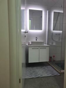 La salle de bains blanche est pourvue d'un lavabo et d'un miroir. dans l'établissement Apartman Valentina, à Trebinje