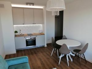 a living room with a table and chairs and a kitchen at Nowy w centrum 2 in Giżycko