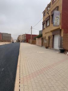 an empty street with a brick sidewalk next to a building at Europa mirlef t aventur Guest House in Mirleft