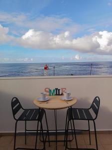 a table with two chairs and a table with a view of the ocean at Cibuqueira numéro 8 , centre ville, vue sur mer, plage à pied in Le Moule