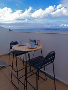 una mesa y sillas en un balcón con vistas al océano en Cibuqueira numéro 8 , centre ville, vue sur mer, plage à pied, en Le Moule