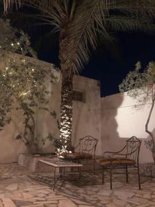 a patio with two chairs and a table and a palm tree at Dar Chahla in Tozeur