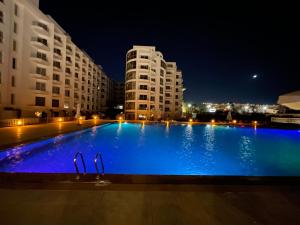 a large blue swimming pool at night with buildings at Scandic Rezort in Hurghada