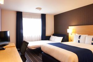 a hotel room with two beds and a television at Holiday Inn Express Manchester Airport, an IHG Hotel in Hale