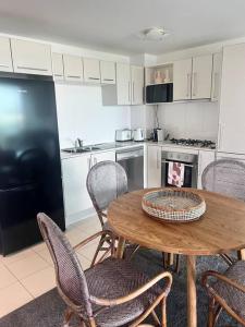 uma cozinha com uma mesa de madeira e cadeiras numa cozinha em Pavillions - Hosted by Burleigh Letting em Gold Coast
