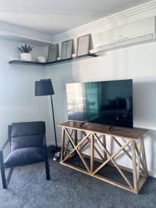 a living room with a television and a chair at Pavillions - Hosted by Burleigh Letting in Gold Coast