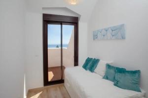 - un canapé blanc avec des oreillers bleus dans une chambre avec une fenêtre dans l'établissement Nuevo apartamento en Benalmádena pueblo con vistas, à Benalmádena