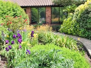 a garden with flowers in front of a house at Riverside Cottage in Costessey
