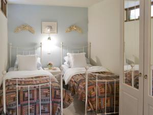 a bedroom with two beds and a mirror at Riverside Cottage in Costessey