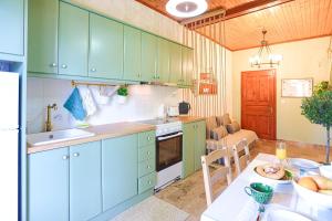 una cocina con armarios verdes y una mesa con mesa en Cochelli Upper Pool Walk to beach AC WiFi, en Ágios Stéfanos