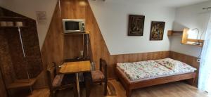 ハイヌフカにあるAgroturystyka Przylesieのベッド1台、壁掛けテレビが備わる小さな客室です。