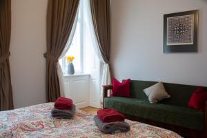 Un dormitorio con un sofá verde y almohadas rojas en una cama. en Stilvolles Apartment in zentraler Lage, en Viena