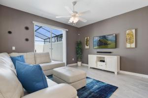 een woonkamer met een witte bank en een plafondventilator bij Four Bedrooms with Screen PoolStoreyLake 4910 in Kissimmee
