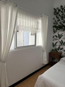 1 dormitorio con una ventana con cortinas blancas en Apartamento Plaza Mayor - Torrelavega, en Torrelavega