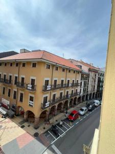 Un gran edificio con coches aparcados en una calle. en Apartamento Plaza Mayor - Torrelavega, en Torrelavega